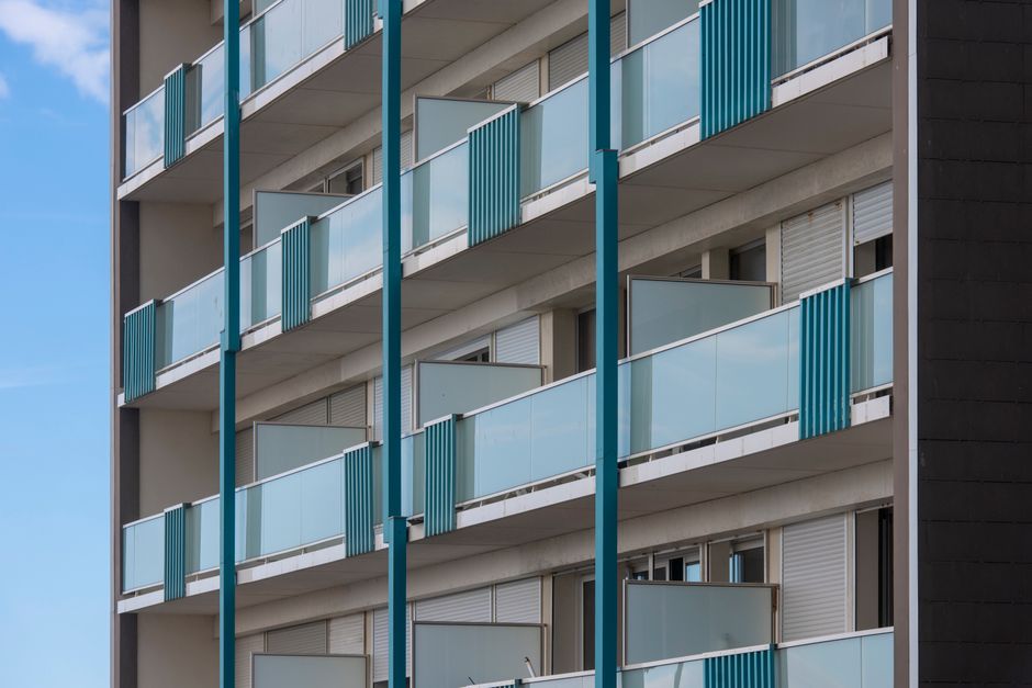 Exterior view of a modern apartment building with multiple blue balconies